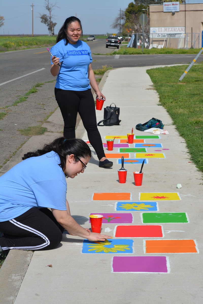 two women painting a sidewalk