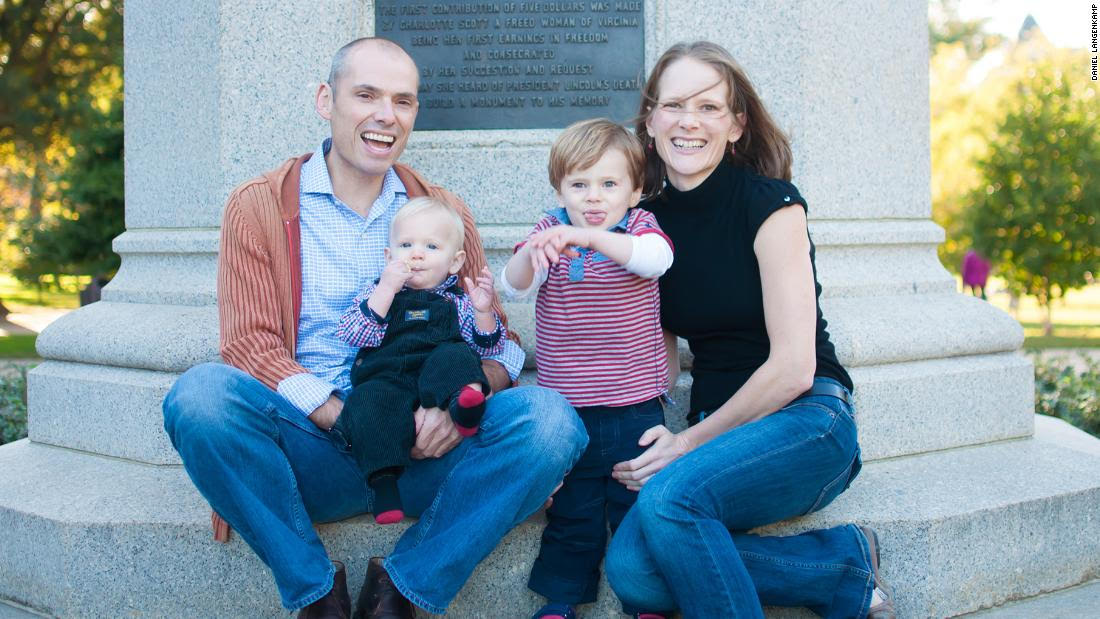 Woman and man smiling sitting down with two small children