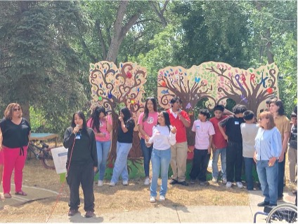 Children and families stand in front of a painted tree display. 