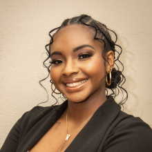 Yoselyn Owolabi Girl with dark hair and dark suit jacket smiling in a professional headshot